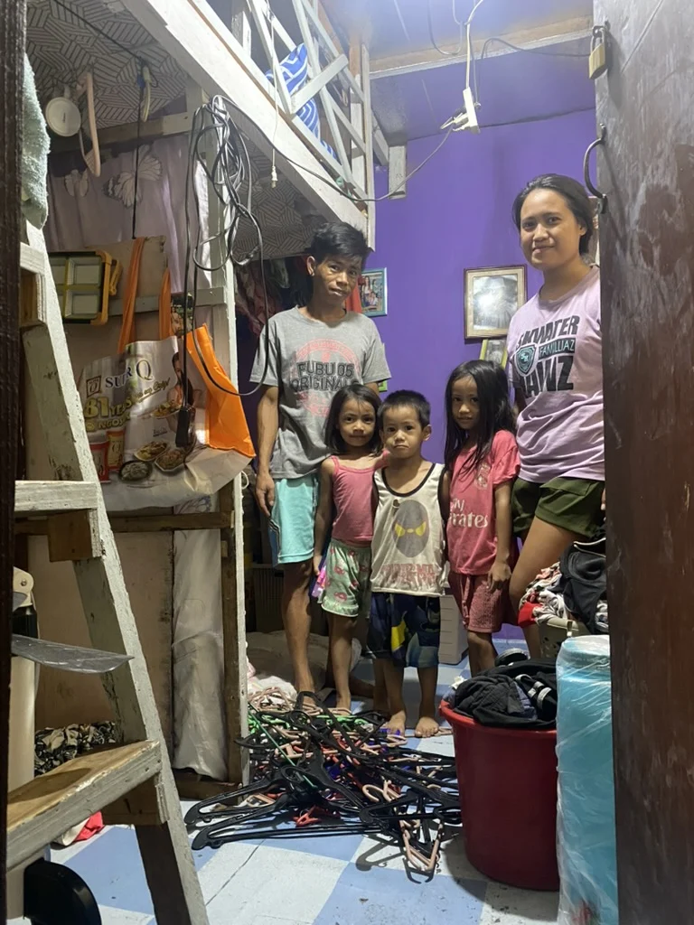 Two adults and three children inside a small home.